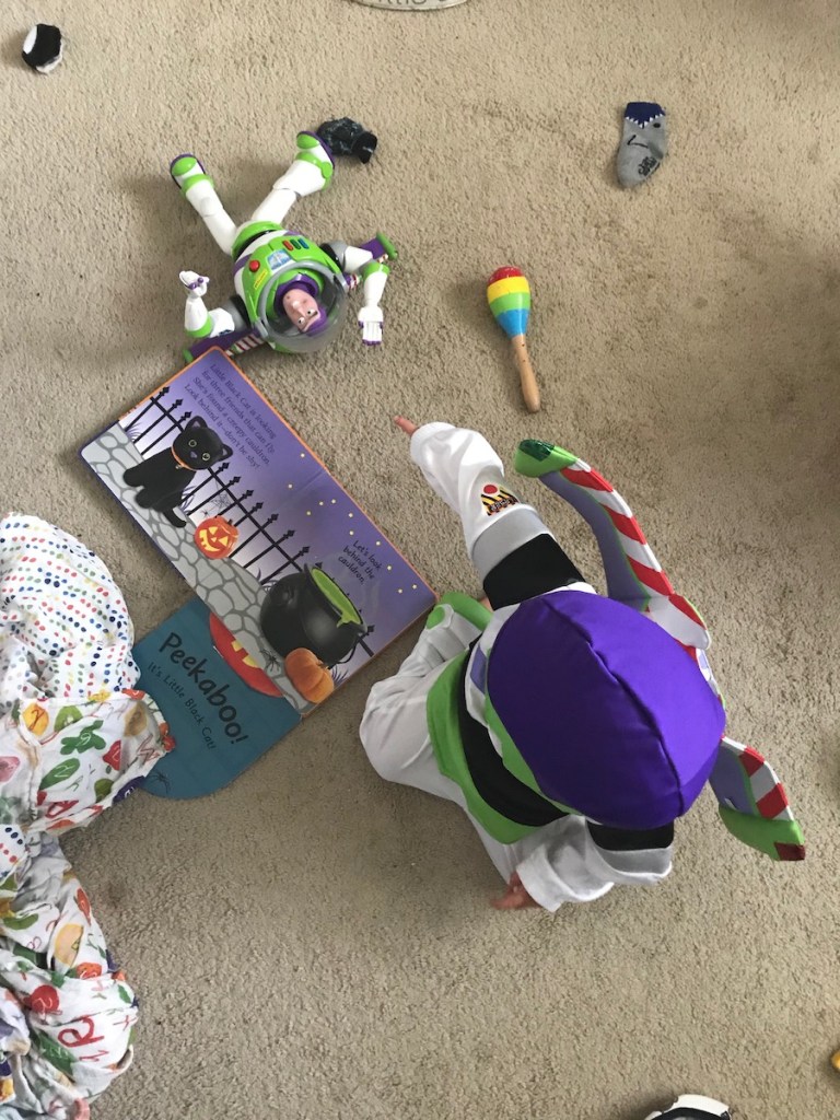 toddler boy dressed in Buzzlightyear costume for Halloween with a buzzlightyear toy from Disneyland