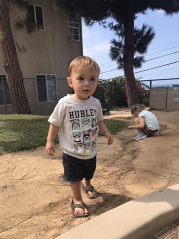 Toddler boy wearing Hurley T-shirt with leather sandals at the park 